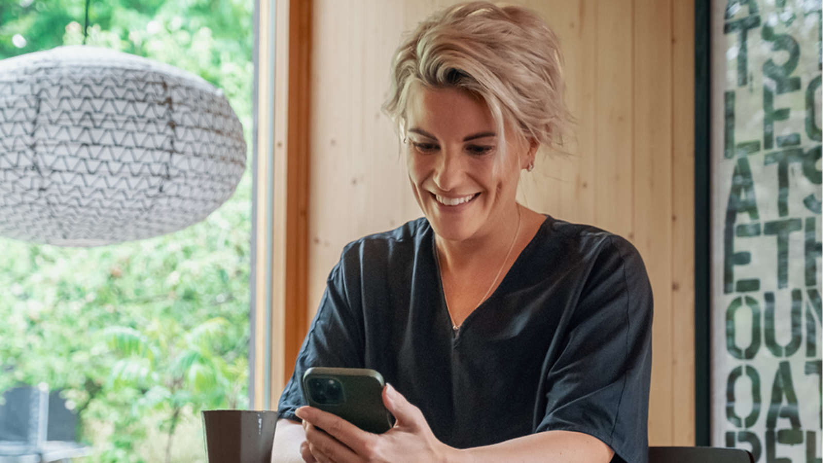 Foto av smilende kvinne som ser på mobilen.